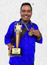 Senpai Andang Putro Lesmono memegang piala dan medali kejuaraan